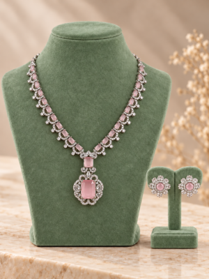 Light pink American Diamond necklace with an ornate pendant and floral stud earrings displayed on sage green stands